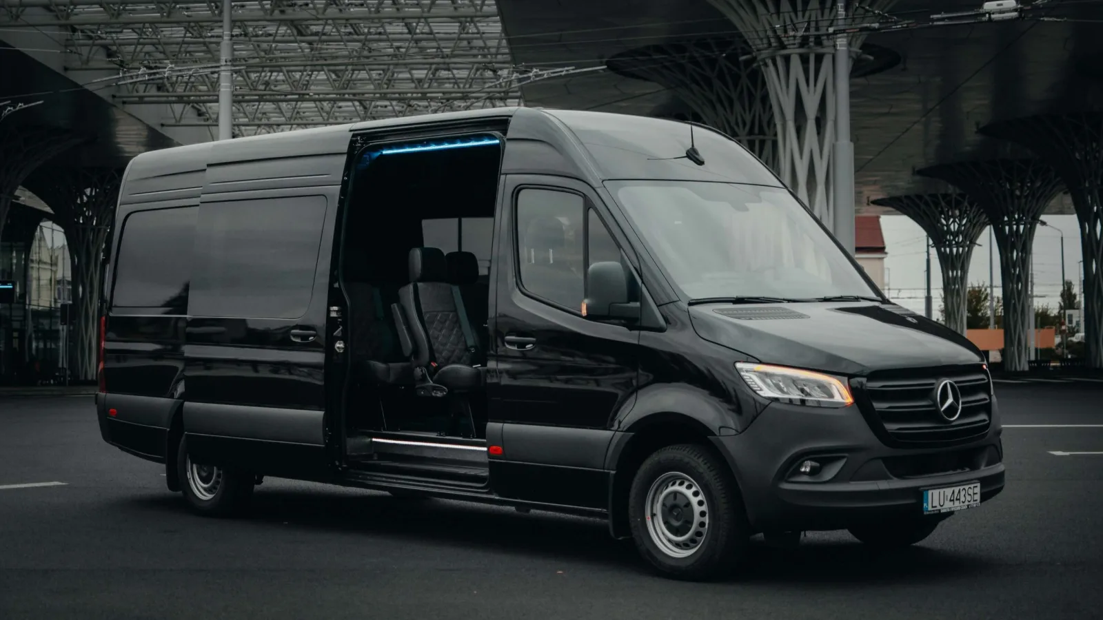 Czarny bus Mercedes Sprinter z otwartymi drzwiami bocznymi